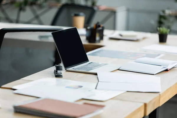 Computer portatile con schermo vuoto vicino a notebook vuoto e documenti sulla scrivania dell'ufficio — Foto stock