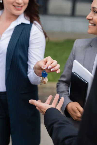 Agente immobiliare offuscata dando la chiave per l'uomo d'affari vicino al suo sorridente collega afroamericano — Foto stock