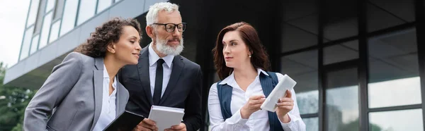 Real estate broker showing digital tablet to interracial business partners outdoors, banner — Stock Photo