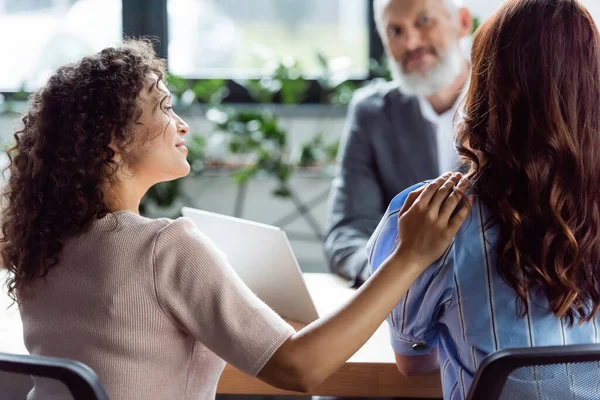 Positivo africano americano mujer tocando hombro de lesbiana novia cerca borrosa real estate agent - foto de stock