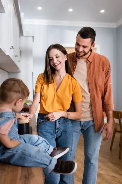 Genitori in piedi vicino al bambino sul piano di lavoro della cucina — Foto stock