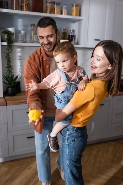 Padre sosteniendo limón cerca de hijo y esposa en casa - foto de stock