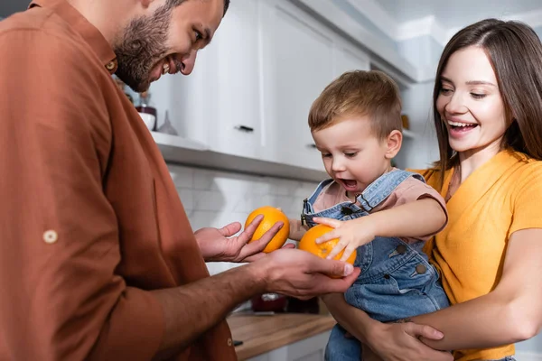 Uomo che tiene le arance vicino a capretto e moglie a casa — Foto stock