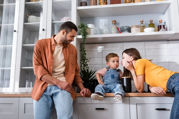 Junge Frau schmollt Lippen neben Sohn und Ehemann zu Hause — Stockfoto