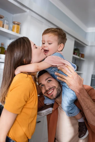 Frau küsst Kind nahe Ehemann zu Hause — Stockfoto