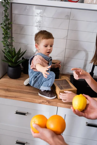 Parents tenant des fruits près de fils tout-petit sur le plan de travail dans la cuisine — Photo de stock