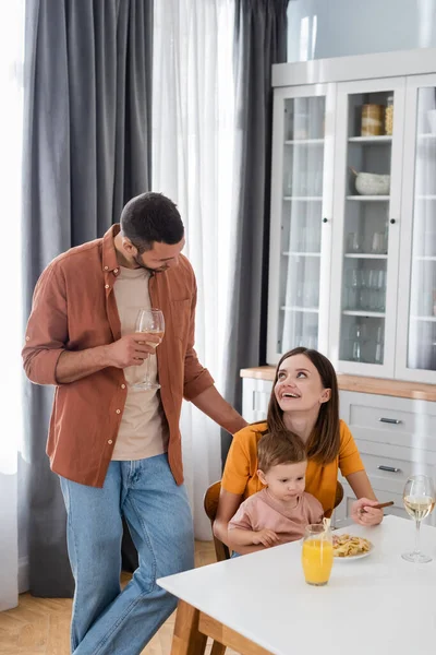Мужчина держит вино рядом с женой и сыном во время ужина дома — стоковое фото