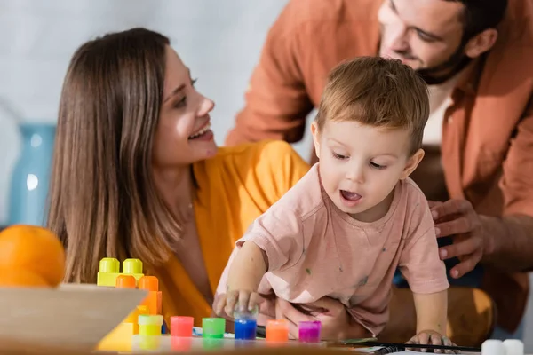 Toddler kid playing with paint near parents at home — Stock Photo