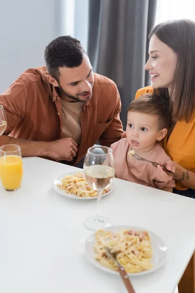 Pais positivos sentados perto do filho e jantar saboroso em casa — Fotografia de Stock