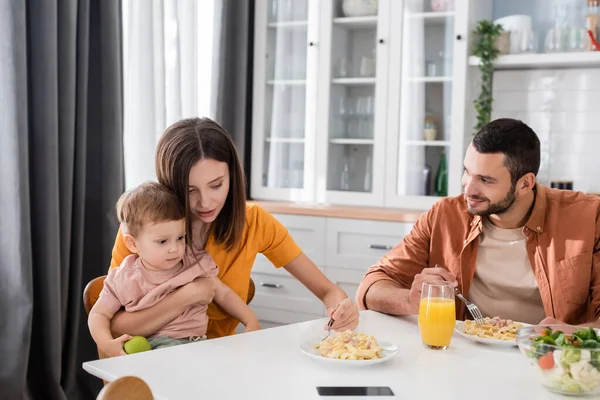Woman hugging son near tasty dinner and husband at home — Stock Photo