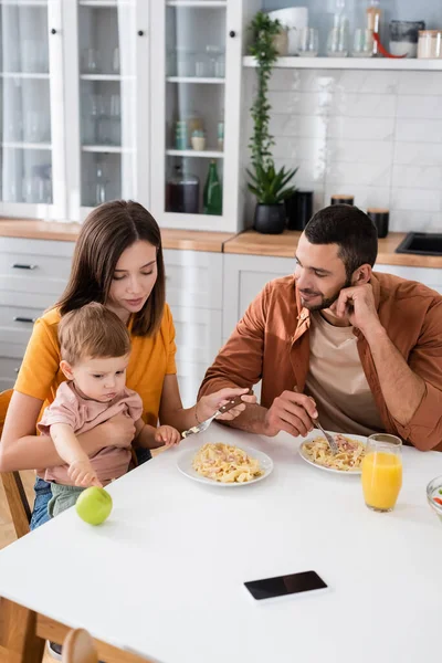 Famiglia e figlio bambino seduto vicino a cena e succo d'arancia a casa — Foto stock