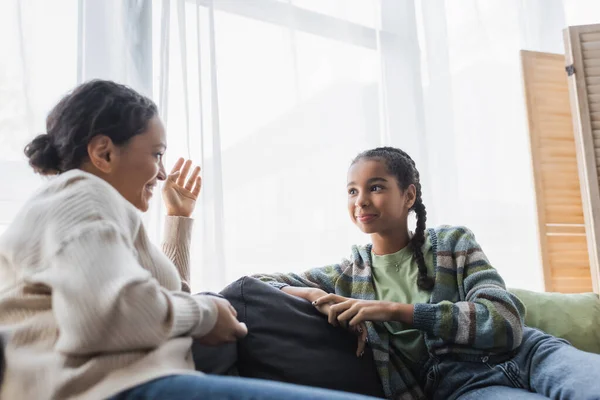 Mulher afro-americana borrada gesticulando enquanto falava com a filha adolescente sorridente — Fotografia de Stock