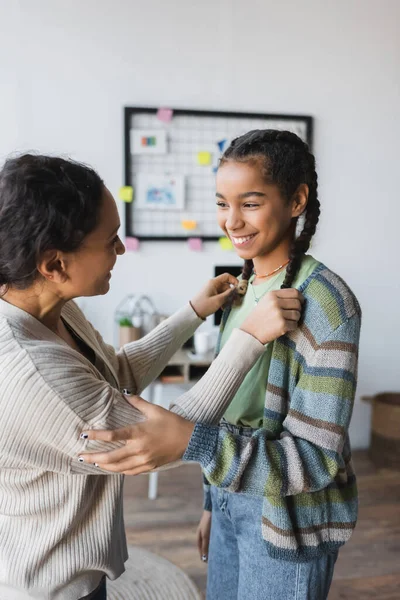 African american woman touching pigtails of happy teenage daughter — Stock Photo