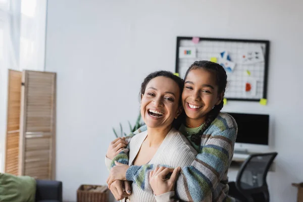 Excited african american girl embracing mother while looking at camera — Stock Photo