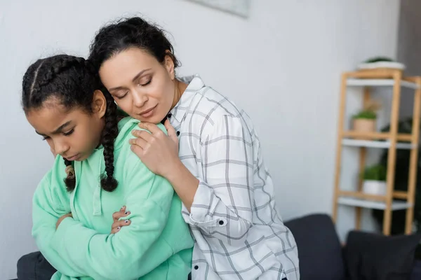 African american woman embracing upset teenage daughter standing with crossed arms — Stock Photo