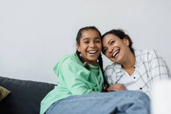 Animado afro-americano mãe e filha rindo no sofá em casa — Fotografia de Stock