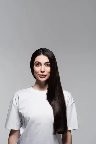 Mujer complacida con el pelo largo y liso aislado en gris - foto de stock