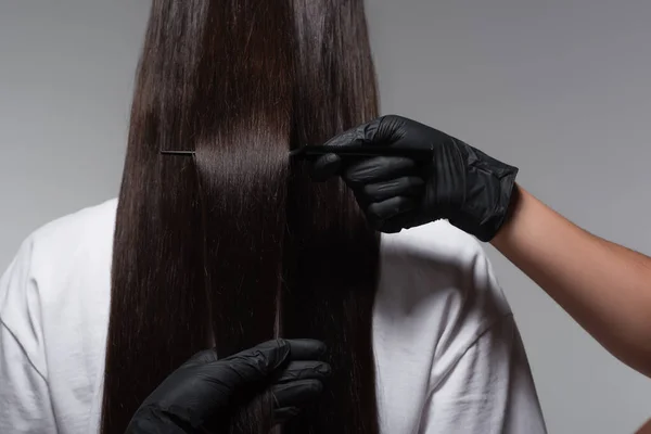Назад вид молодой женщины с гладкими длинными волосами рядом колорист в латексных перчатках изолированы на сером — стоковое фото