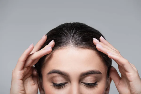 Abgeschnittene Ansicht eines jungen Models mit braunen Haaren, das vereinzelt auf grau herabblickt — Stockfoto