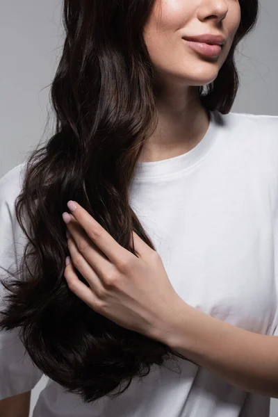 Abgeschnittene Ansicht einer jungen, fröhlichen Frau mit langen welligen Haaren isoliert auf grau — Stockfoto