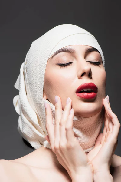 Young woman in elastic bandage on head and closed eyes isolated on grey — Stock Photo