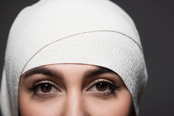 Cropped view of young woman in elastic bandage on head looking at camera isolated on grey — Stock Photo