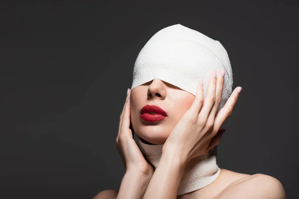 Mujer tocando vendaje elástico con los ojos cubiertos aislados en gris - foto de stock