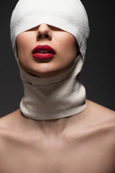 Jeune femme en bandage élastique avec yeux couverts et lèvres rouges isolées sur gris — Photo de stock