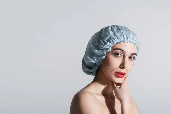 Woman in blue surgical cap with bare shoulders and marked lines on face isolated on grey — Stock Photo