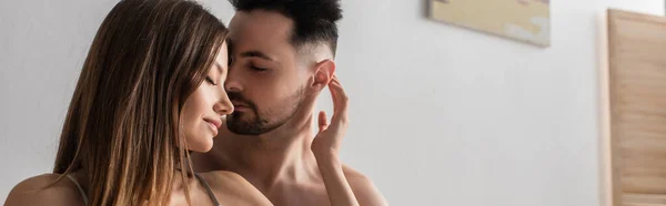 Jóvenes y sexys amantes abrazando con los ojos cerrados en el dormitorio, pancarta — Stock Photo