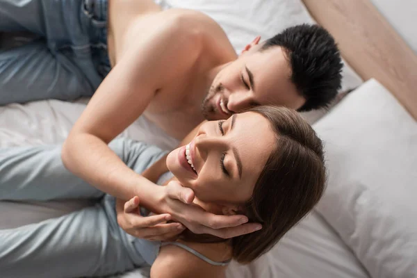 Overhead view of sexy woman smiling with closed eyes near blurred shirtless boyfriend — Foto stock