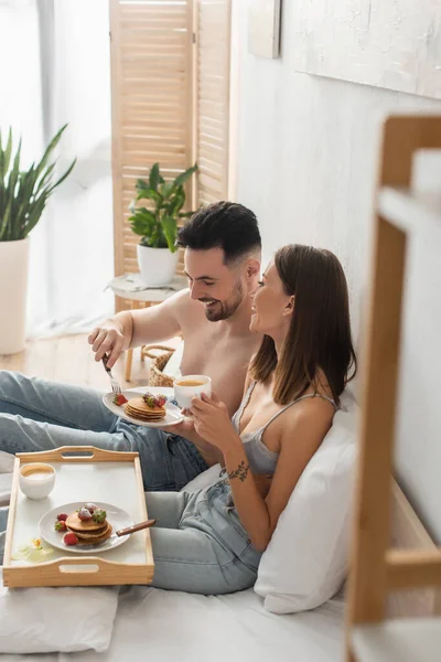 Vista de ángulo alto de sexy pareja joven desayunando en la cama - foto de stock