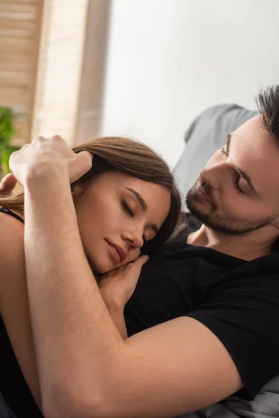 Young man embracing pretty woman sleeping on his chest at home — Photo de stock