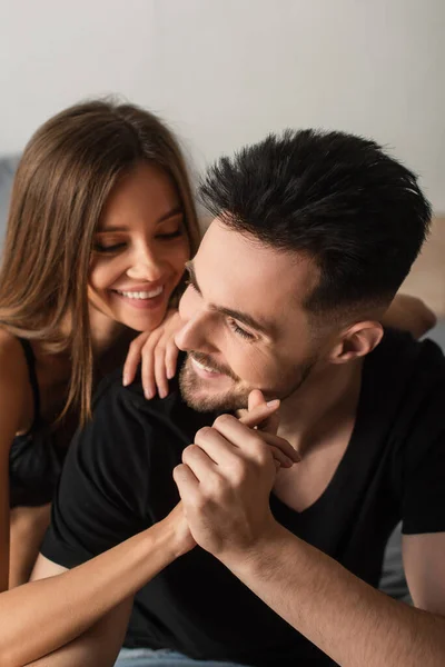 Happy young couple holding hands and smiling in bedroom — стоковое фото