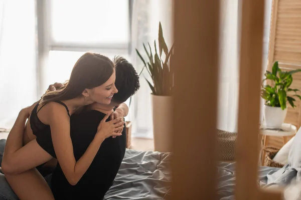 Happy woman in lingerie embracing man in black t-shirt on blurred foreground — Stock Photo