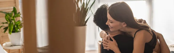 Smiling woman in black bra hugging boyfriend on blurred foreground, banner — Stockfoto