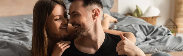 Joven y feliz pareja sonriendo mientras se miran en el dormitorio, pancarta - foto de stock