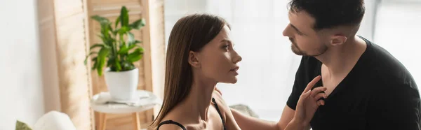 Vista lateral de la joven sensual mujer mirando novio en camiseta negra, bandera - foto de stock