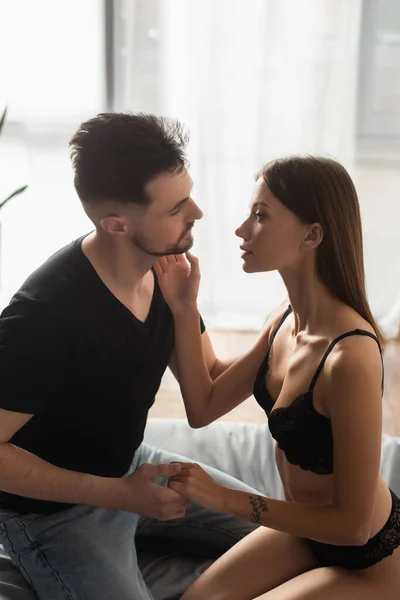 Passionate woman touching face of boyfriend holding her hand in bedroom — Foto stock