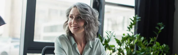 Positive reife Geschäftsfrau, die im Amt wegschaut, Banner — Stockfoto