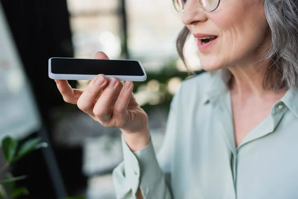 Cropped view of grey haired businesswoman recording voice message on cellphone in office — Stock Photo