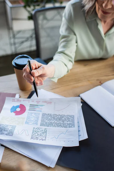 Vista ritagliata della donna d'affari che tiene la penna vicino a carte con grafici in ufficio — Foto stock