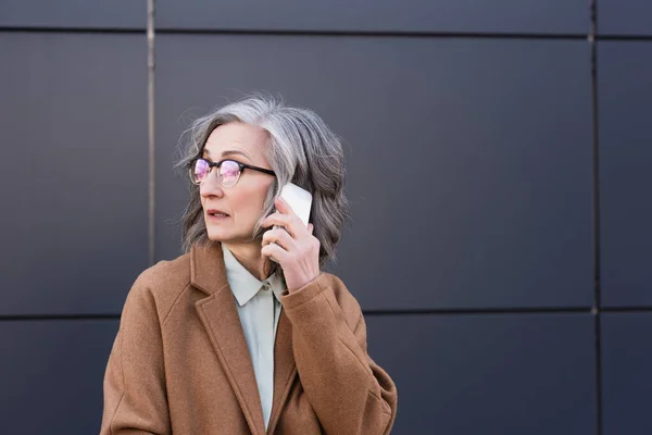 Manager d'âge moyen en manteau parlant sur téléphone mobile en plein air — Photo de stock