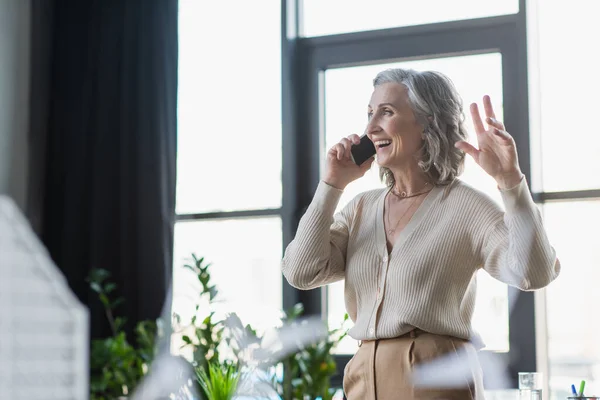 Cheerful businesswoman talking on cellphone in office — Stock Photo