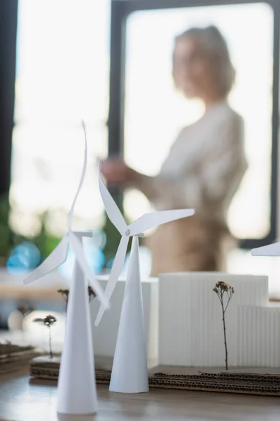 Models of wind turbines and buildings on table in office — Stock Photo