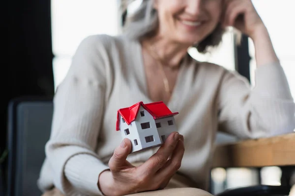 Ausgeschnittene Ansicht des Hausmodells in der Hand einer verschwommenen Geschäftsfrau im Amt — Stockfoto