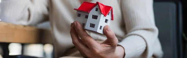 Cropped view of model of building in hand of blurred businesswoman, banner — Stock Photo