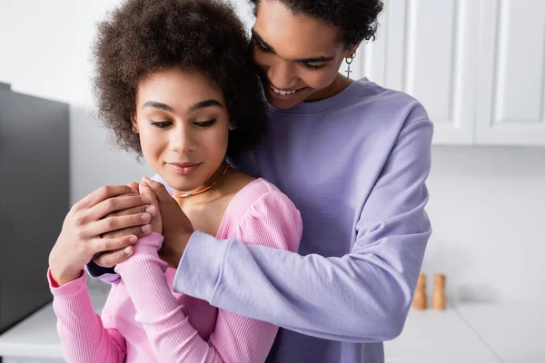 Joven afroamericano hombre cogido de la mano de novia en la cocina - foto de stock