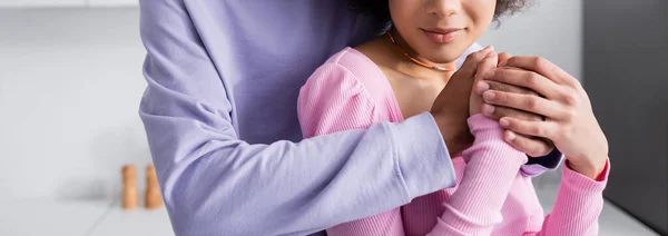 Vista recortada del hombre afroamericano cogido de la mano de su novia en casa, pancarta - foto de stock