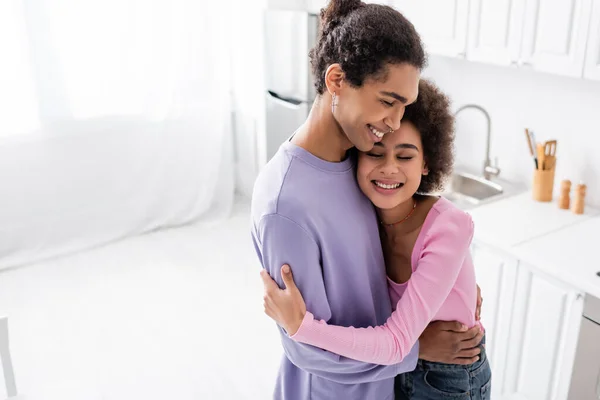 Vue grand angle de couple afro-américain heureux étreignant dans la cuisine — Photo de stock